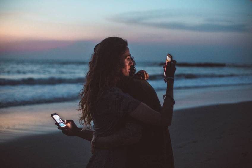 Two people hugging looking at their phones; control your Internet
